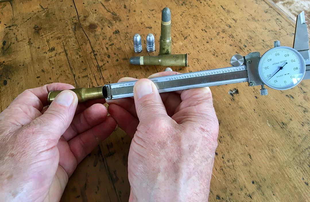 Measuring the distance from case mouth to the powder column using a dial caliper.